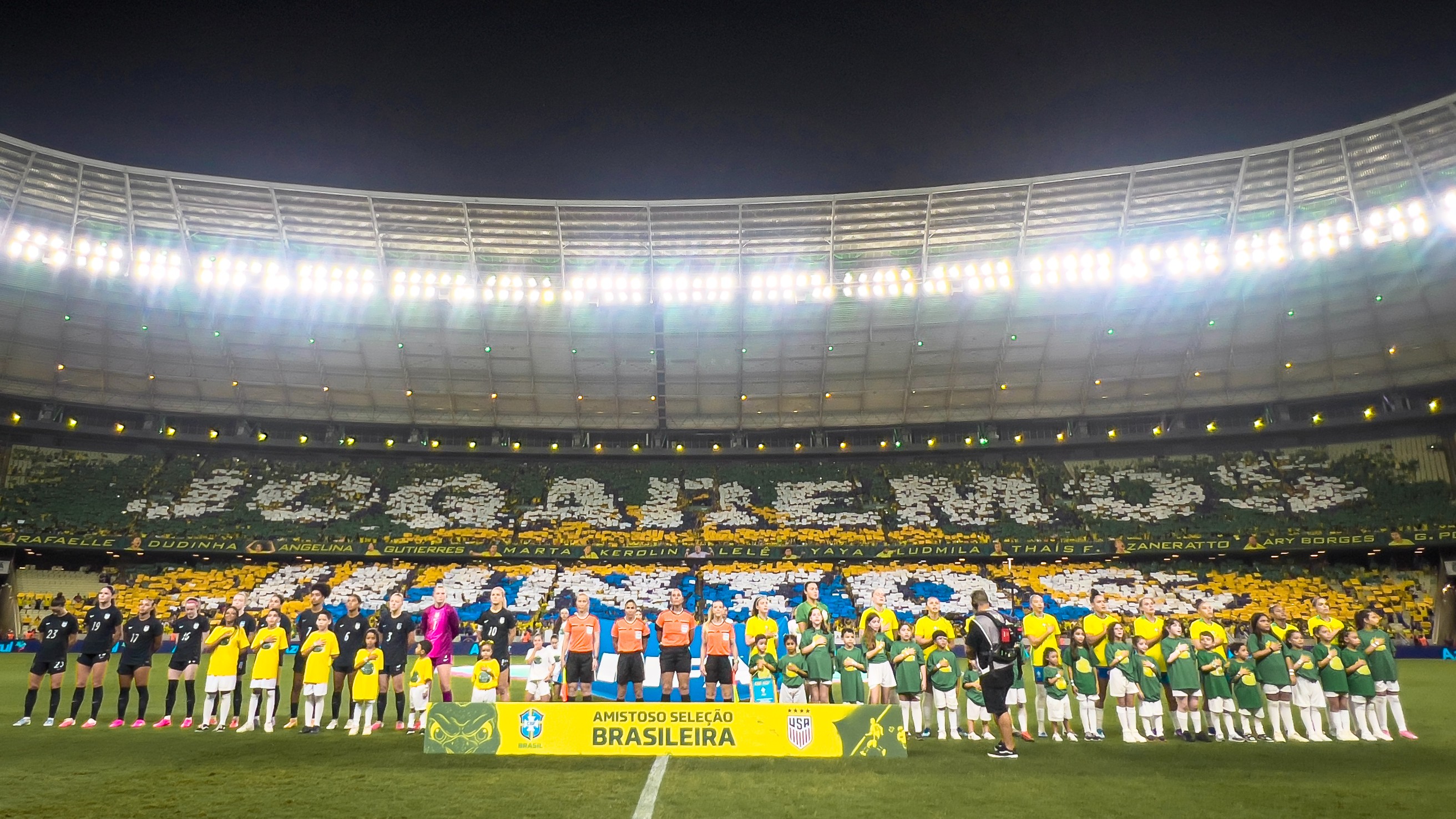 seleções femininas do Brasil e dos Estados Unidos perfiladas no gramado do Castelão